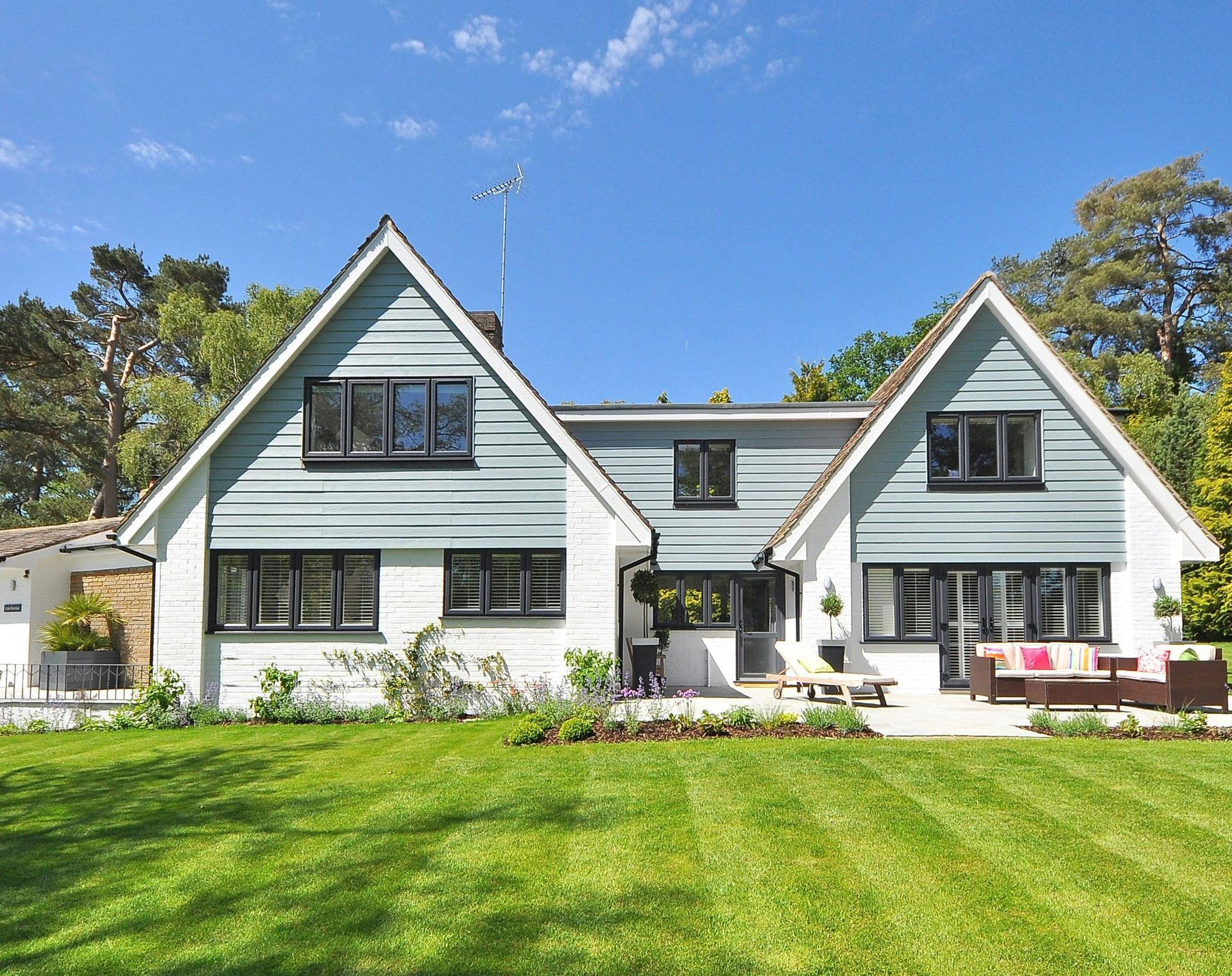 House with light blue siding, white trim, and a green lawn under a blue sky.