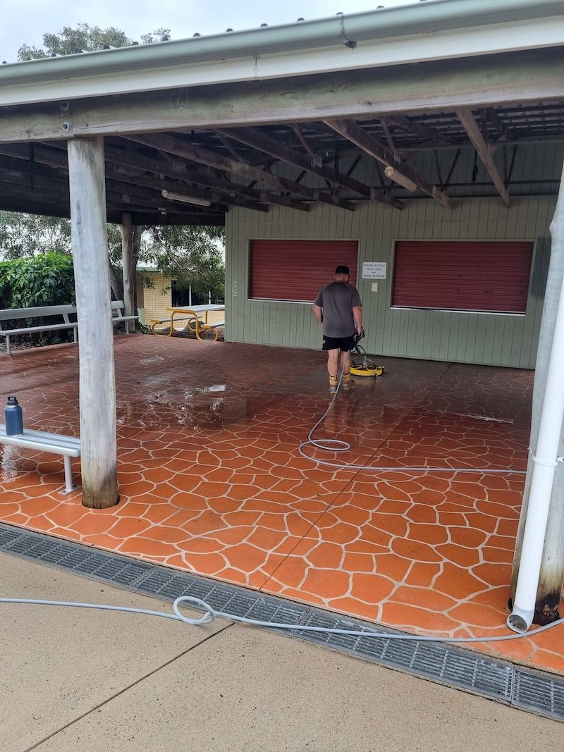 A man in a Yellow Jacket is Standing under a Wooden Structure — Cap Coast Pressure Cleaning in Lammermoor, QLD