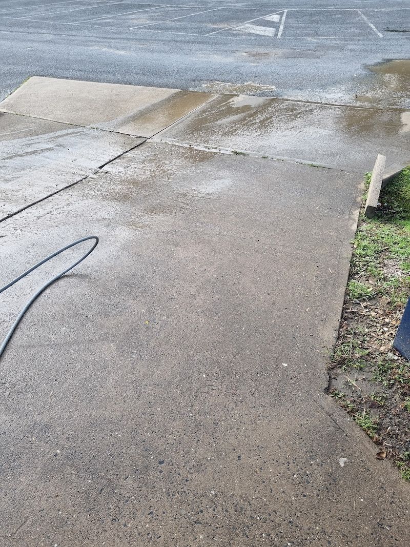 A Person In Orange Pants Is Walking Down The Street With A Broom — Cap Coast Pressure Cleaning in Lammermoor, QLD