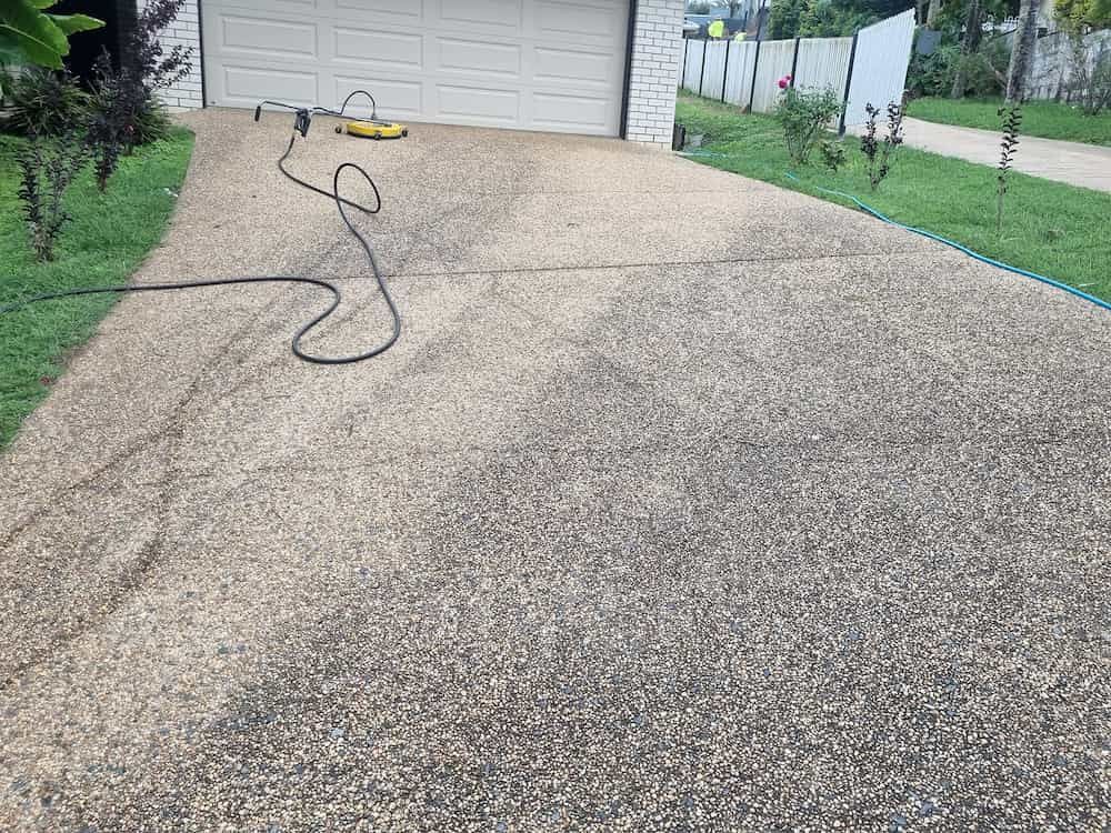 A Concrete Driveway With A Hose Attached To It In Front Of A Garage — Cap Coast Pressure Cleaning in Lammermoor, QLD