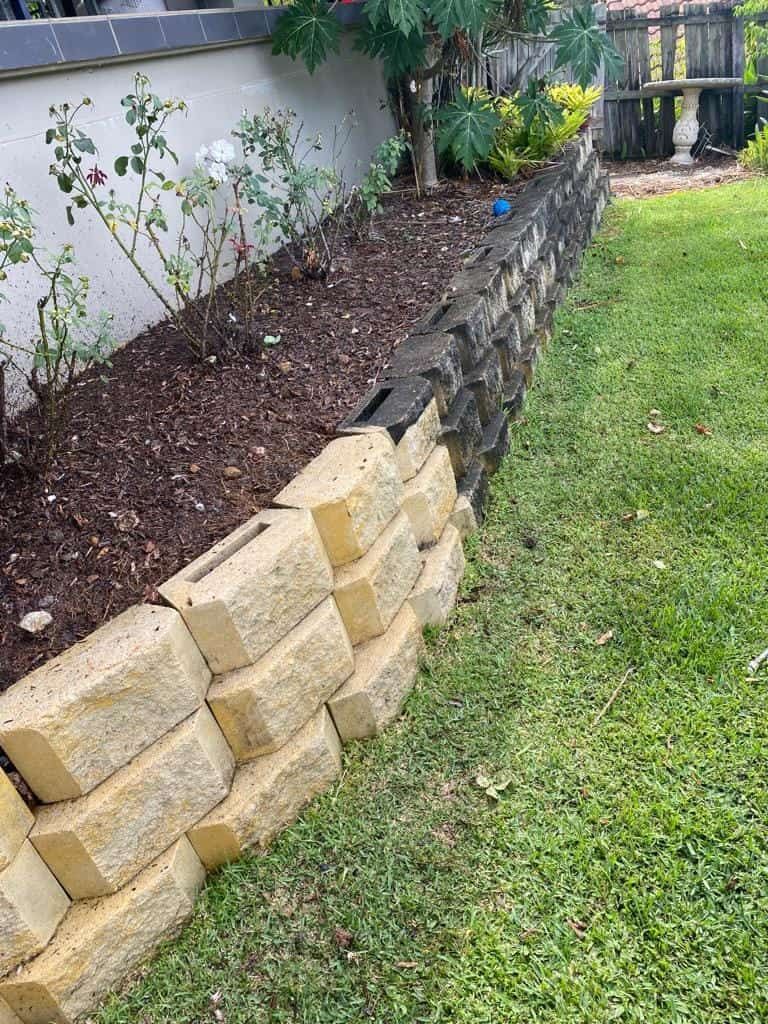 A Stone Wall Surrounding A Garden In A Backyard — Cap Coast Pressure Cleaning in Lammermoor, QLD