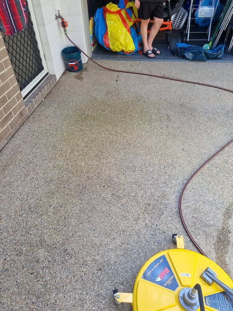 A Person Is Standing On A Concrete Floor Next To A Yellow Machine — Cap Coast Pressure Cleaning in Lammermoor, QLD