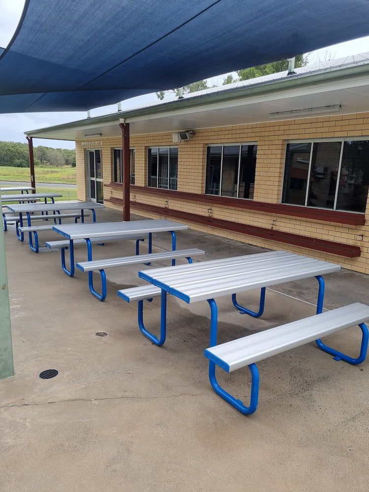 A Row Of White Picnic Tables With Blue Benches Under A Blue Umbrella — Cap Coast Pressure Cleaning in Lammermoor, QLD