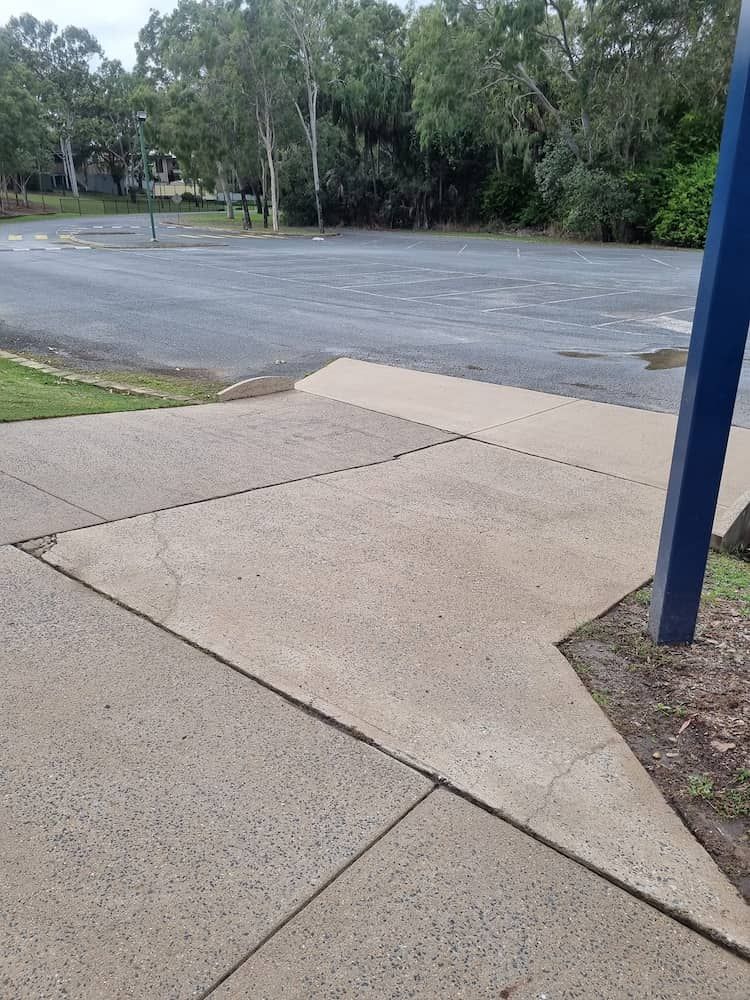 A Concrete Sidewalk Leading To A Parking Lot With Trees In The Background — Cap Coast Pressure Cleaning in Lammermoor, QLD
