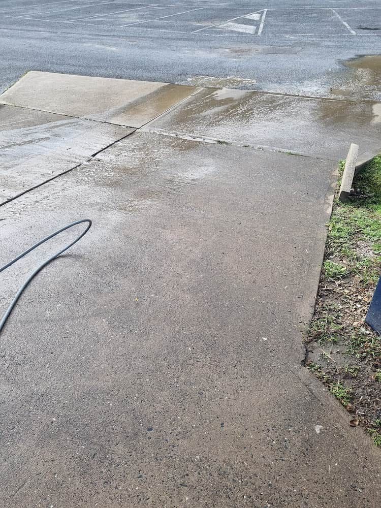 A Person Is Cleaning A Sidewalk With A Pressure Washer — Cap Coast Pressure Cleaning in Lammermoor, QLD