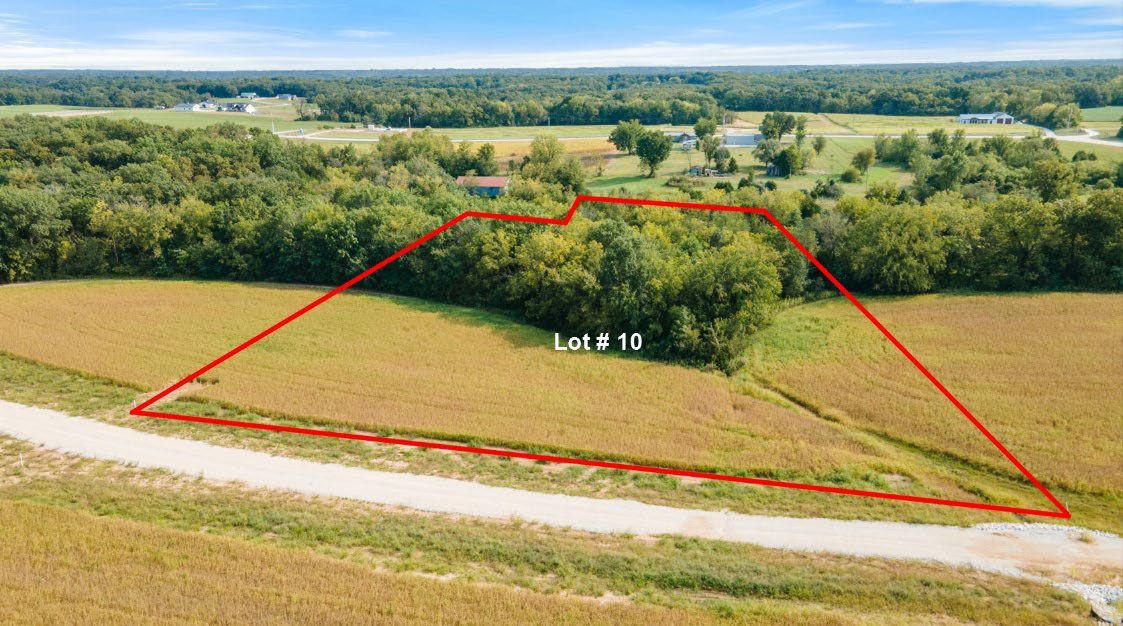 A grassy field bordered in red, next to a road and farmland.