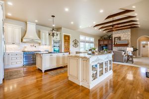 A large kitchen with a large island in the middle of it and hardwood floors.