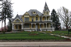 A large yellow house with a black fence around it