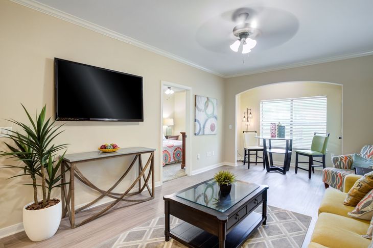 Bedroom with wooden furniture, patterned quilt, turquoise lamps, and window with sheer curtains.