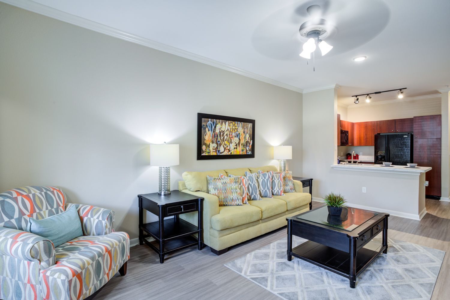 Bay Vista spacious living room with sofa, coffee table, wall art, and ceiling fan.