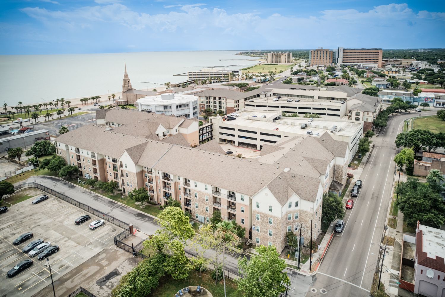 Lobby with seating: patterned armchairs, sofa with decorative pillows, coffee table, desk area, and windows.