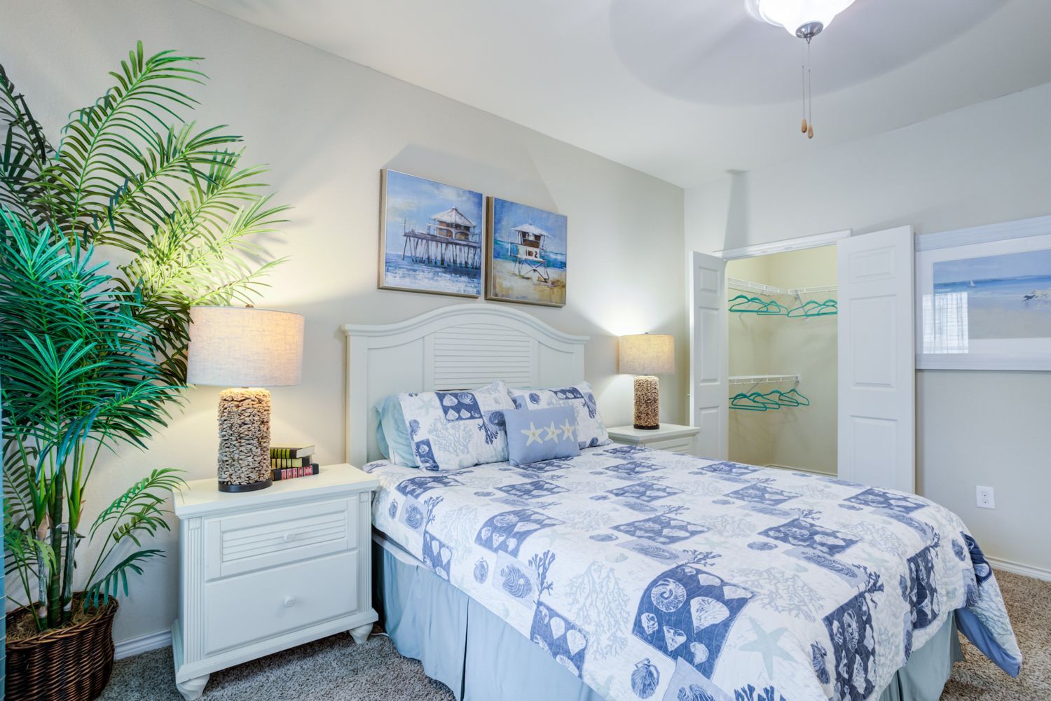 Living room with blue sofa, glass coffee table, gray chair, and abstract art.