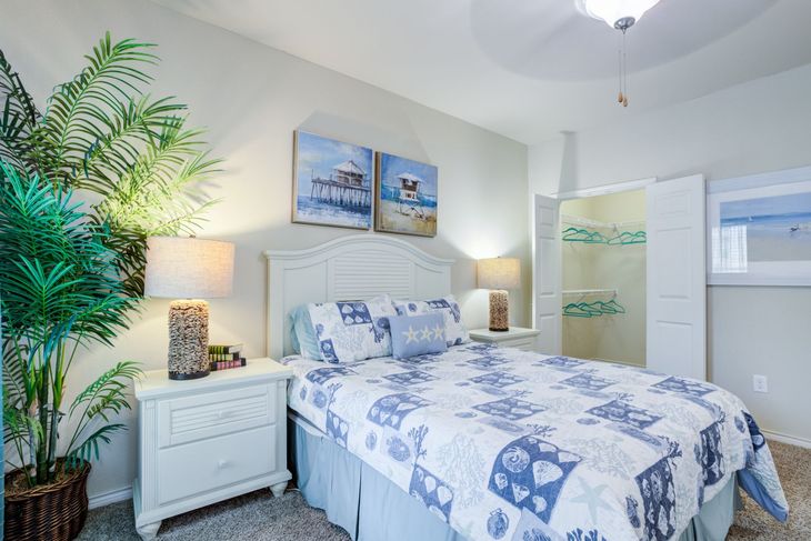Living room with blue sofa, glass coffee table, gray chair, and abstract art.