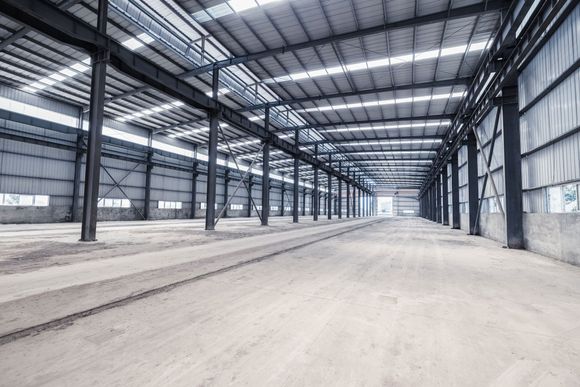 A large empty warehouse with a metal roof and a lot of windows.