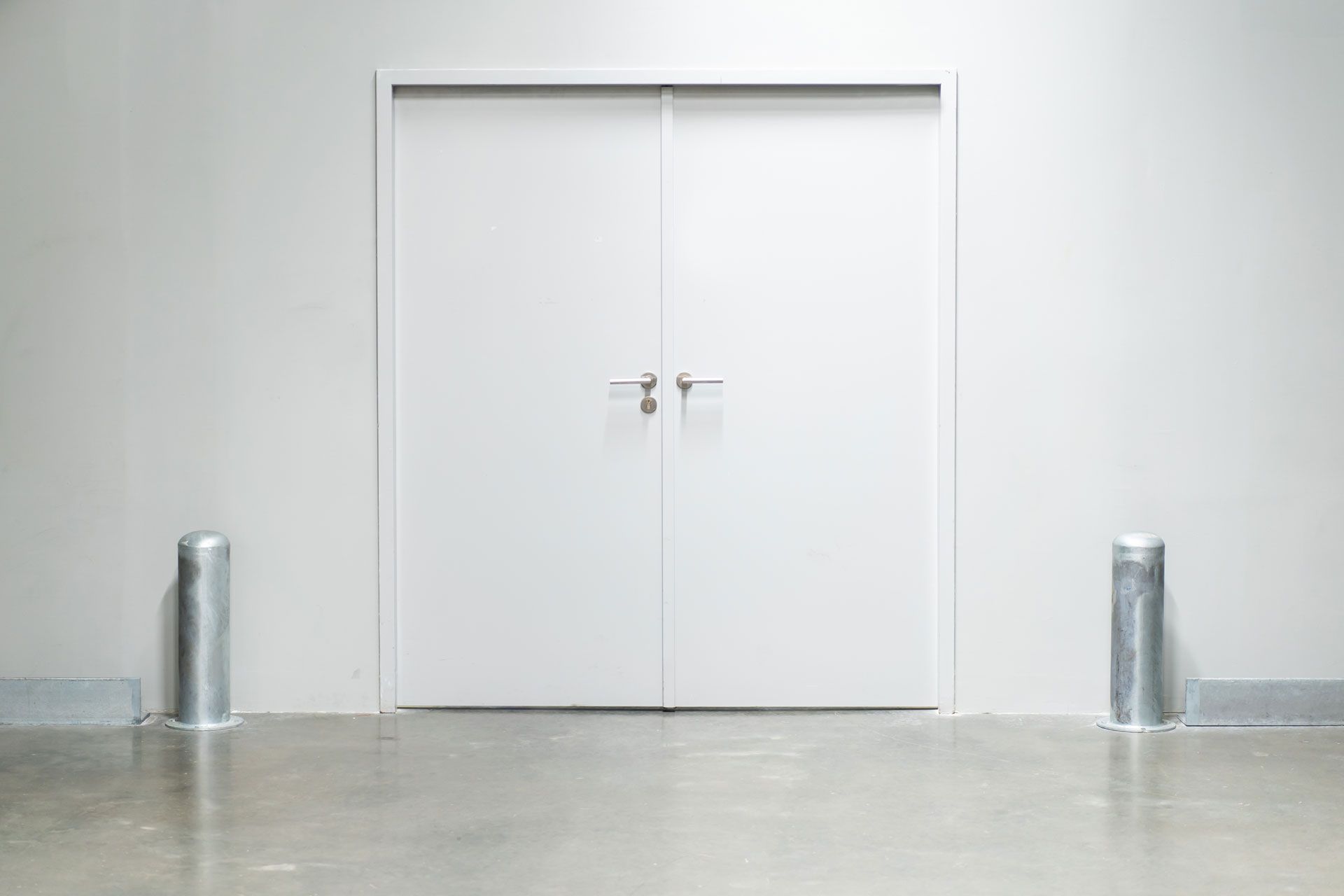 There are two metal poles in front of a white door.