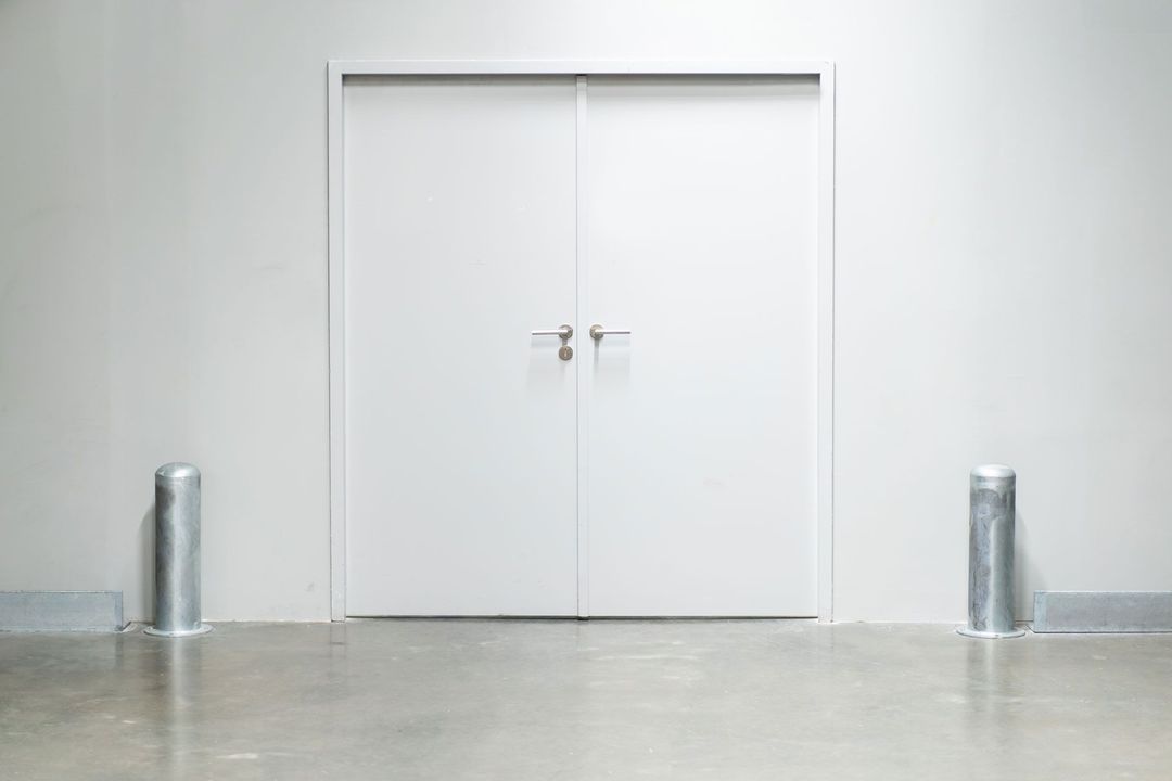 There are two metal poles in front of a white door.
