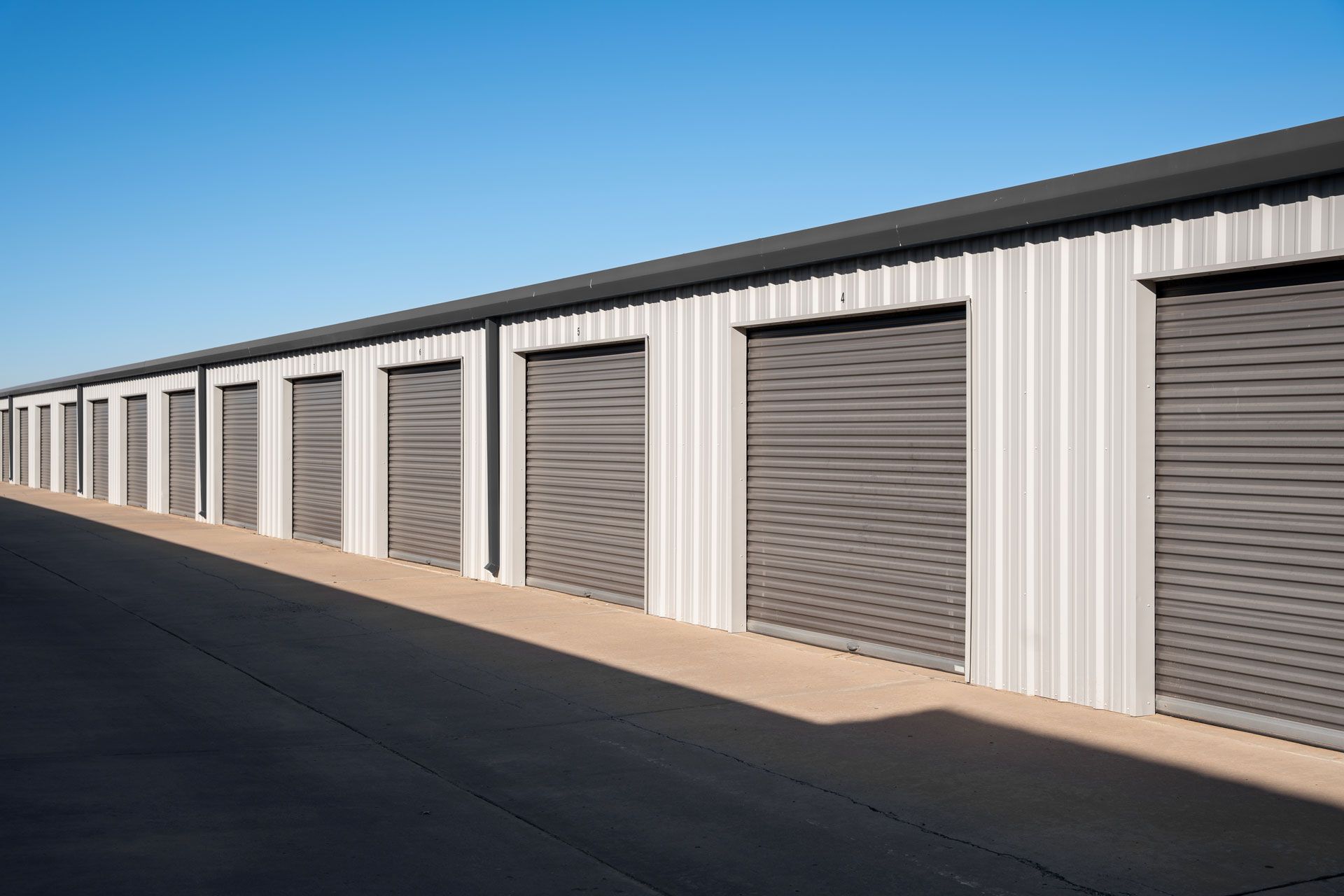 A row of storage units with roller doors on a sunny day.