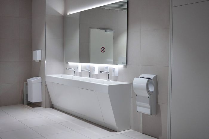 A bathroom with three sinks , a toilet and a mirror.