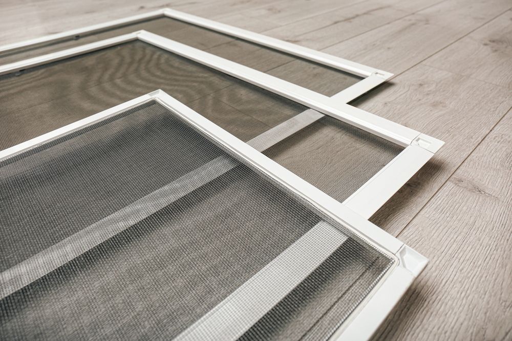 Three mosquito screens are stacked on top of each other on a wooden floor.