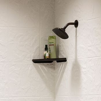 A shower head is hanging from the wall next to a shelf with shampoo bottles on it.