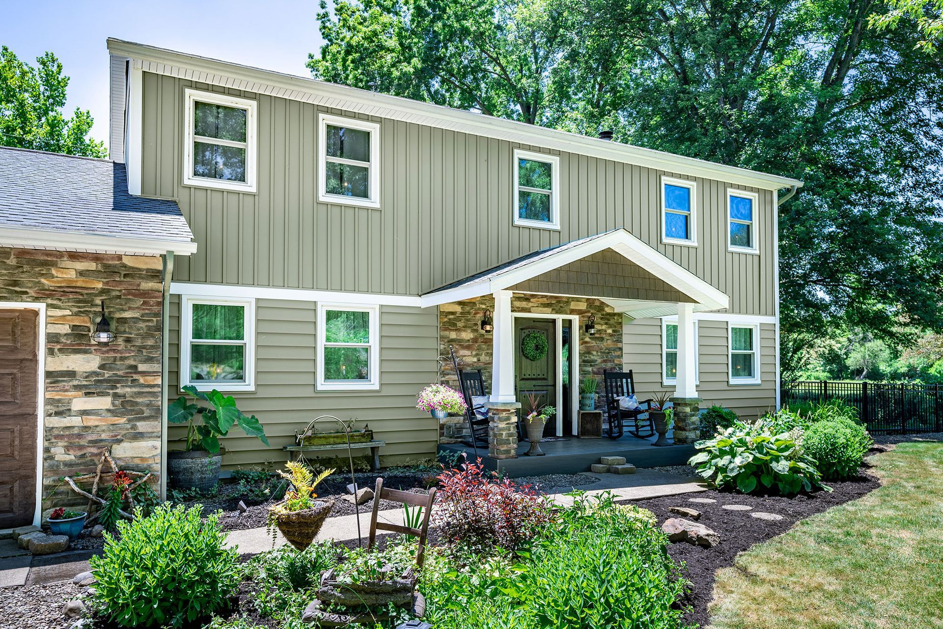 A large house with a lot of windows and a porch surrounded by trees.
