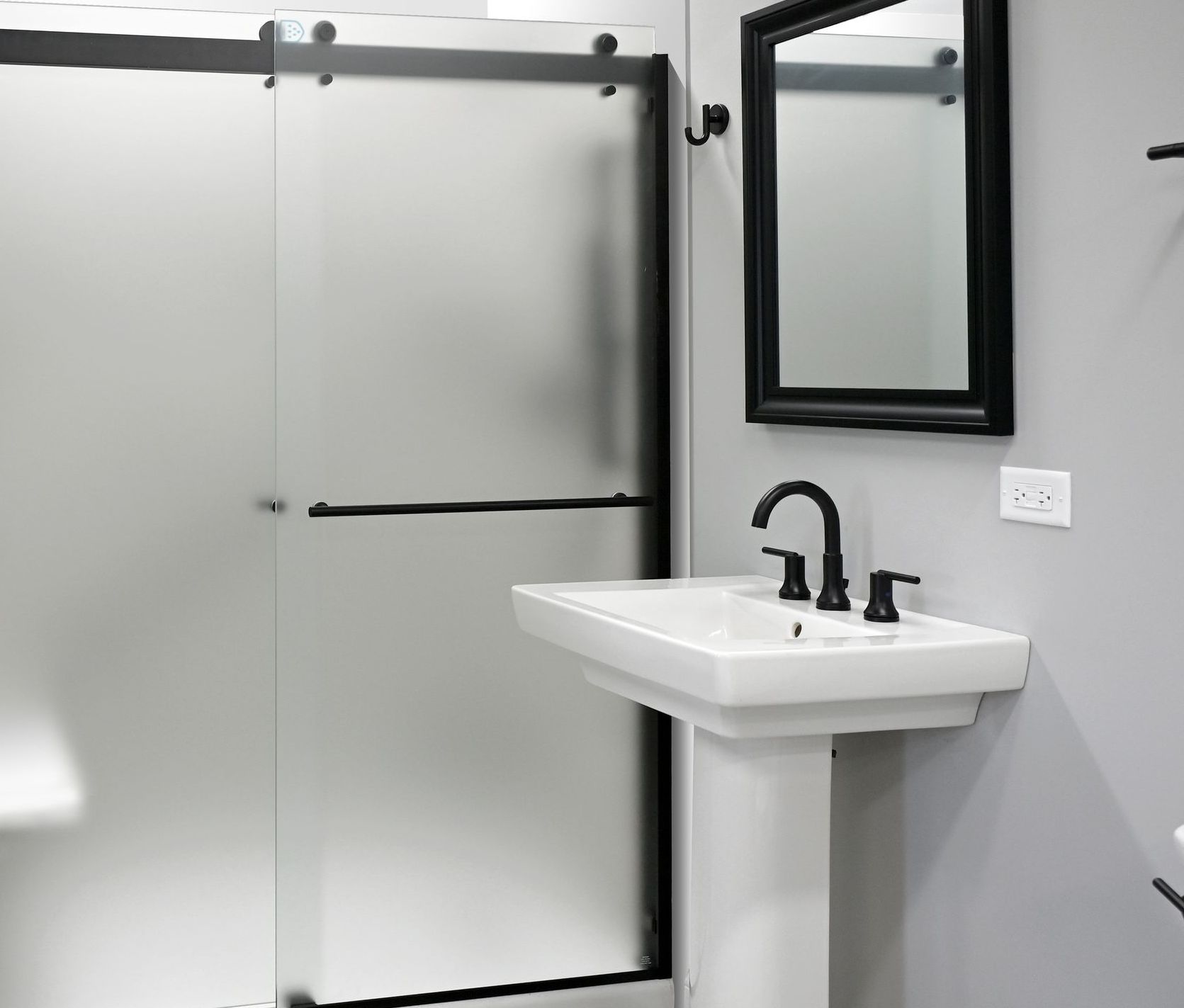 A bathroom with a sink a mirror and a sliding glass shower door