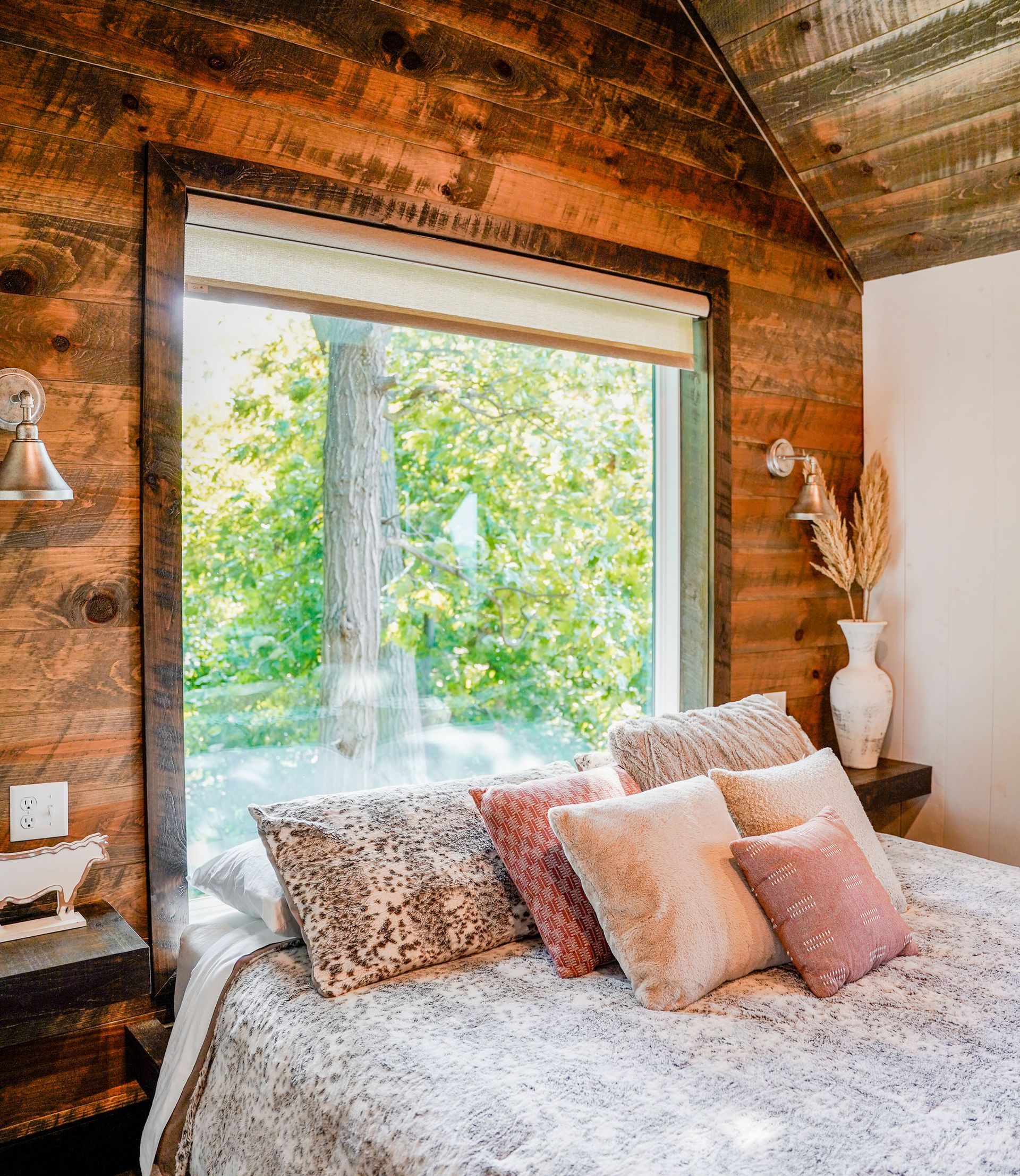 A bedroom with a bed and a window with a view of trees.
