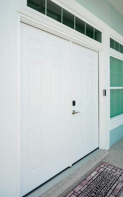 A white garage door with a welcome mat in front of it