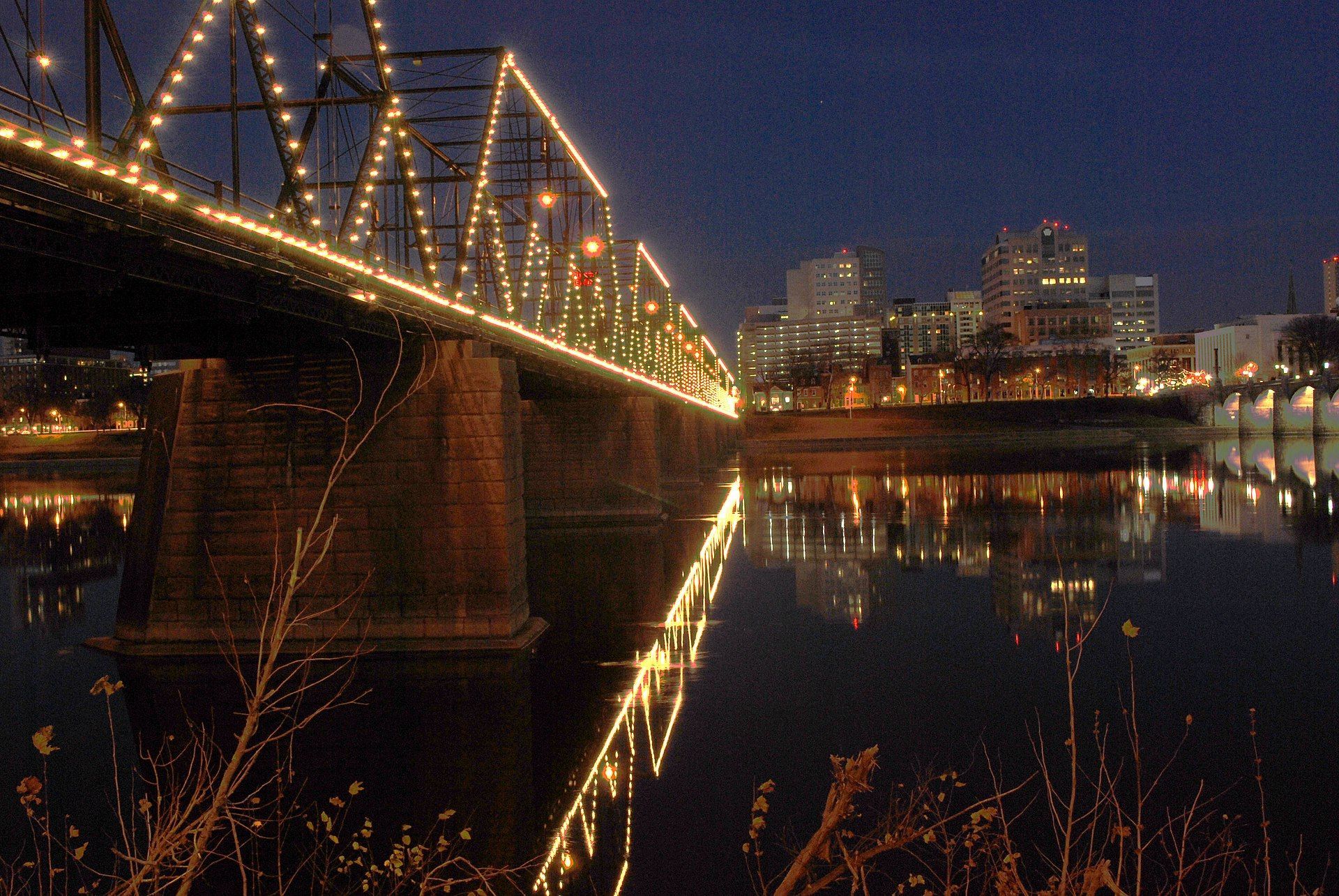 A bridge over a body of water is lit up at night