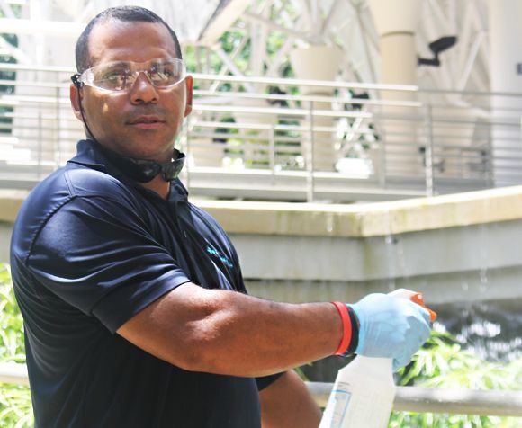 A man wearing safety glasses and blue gloves