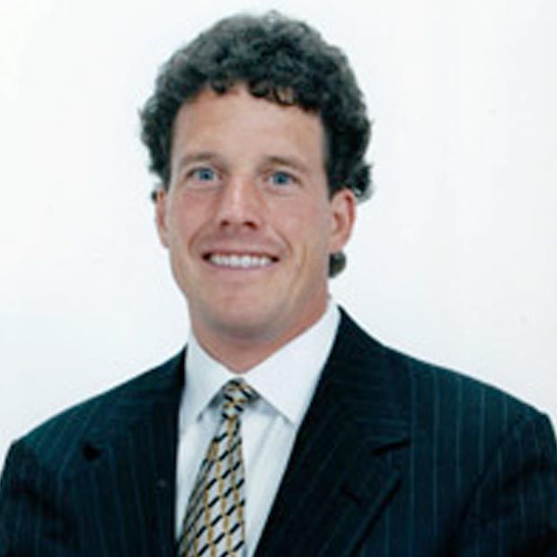 A man in a suit and tie is smiling for the camera