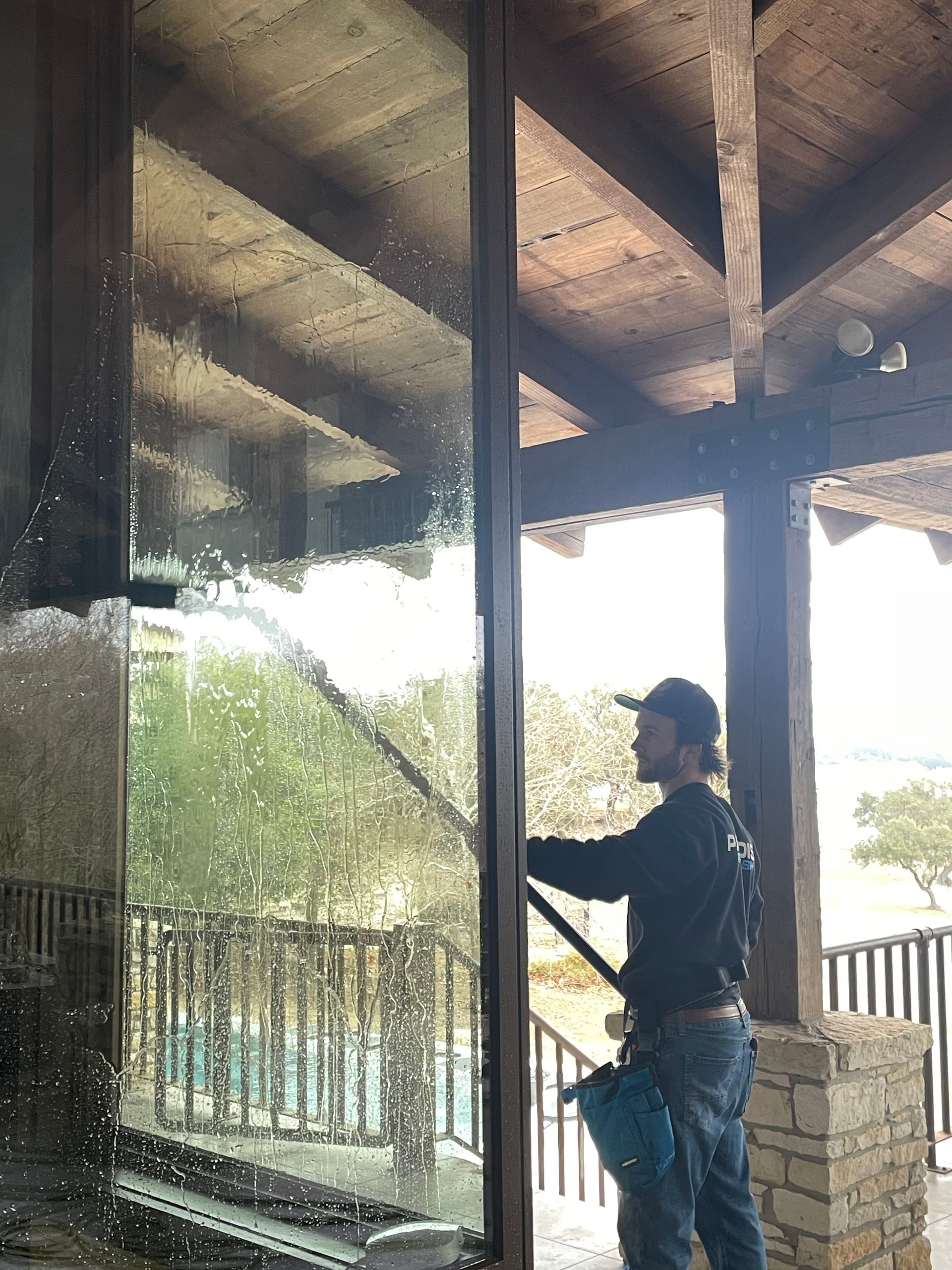 A man wearing a straw hat is cleaning a window