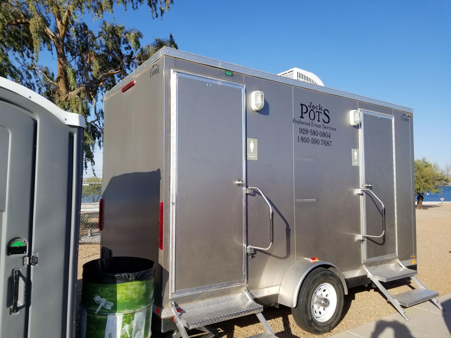 A portable toilet is parked next to a trailer.
