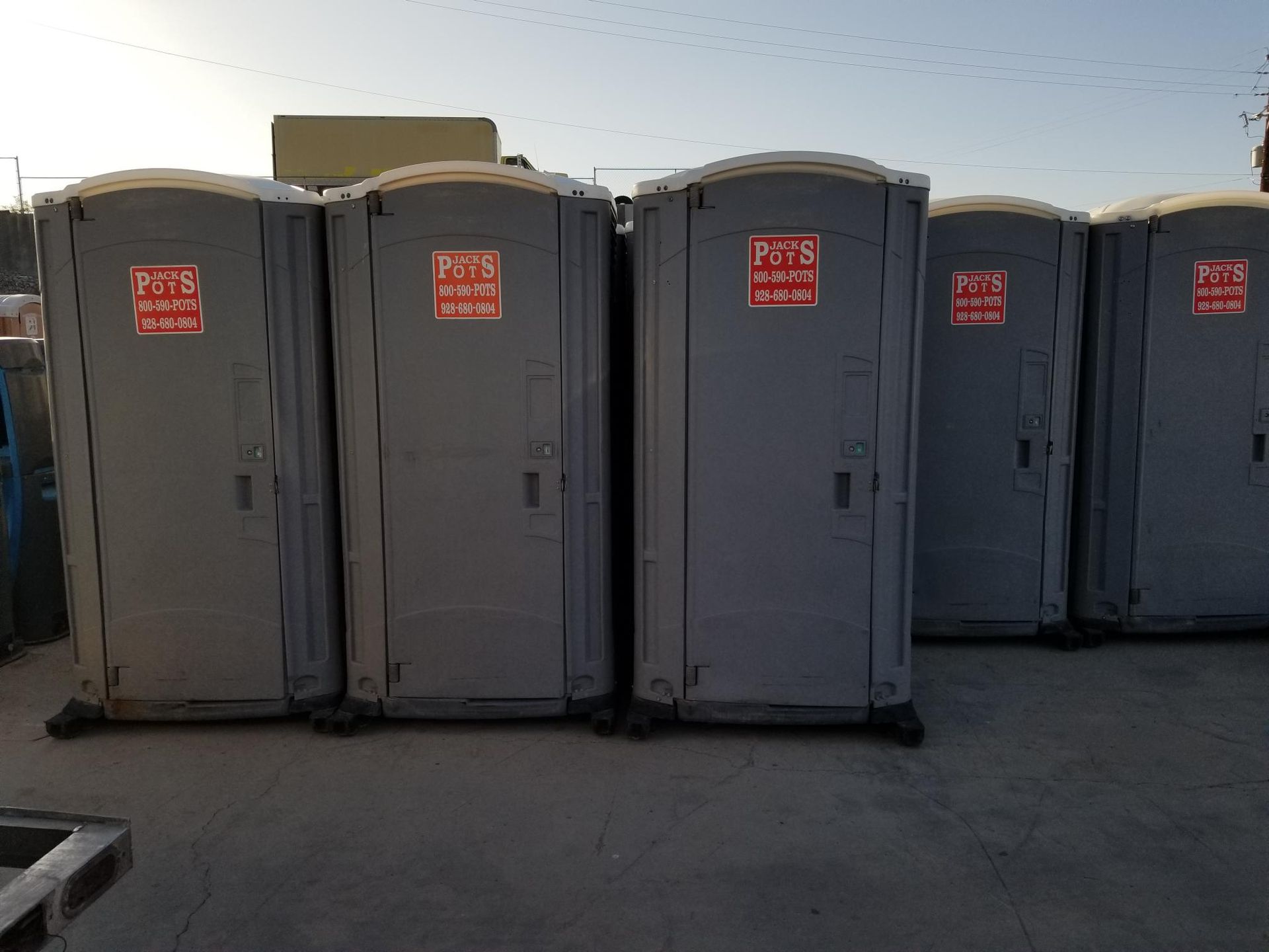 A row of portable toilets are lined up in a parking lot.