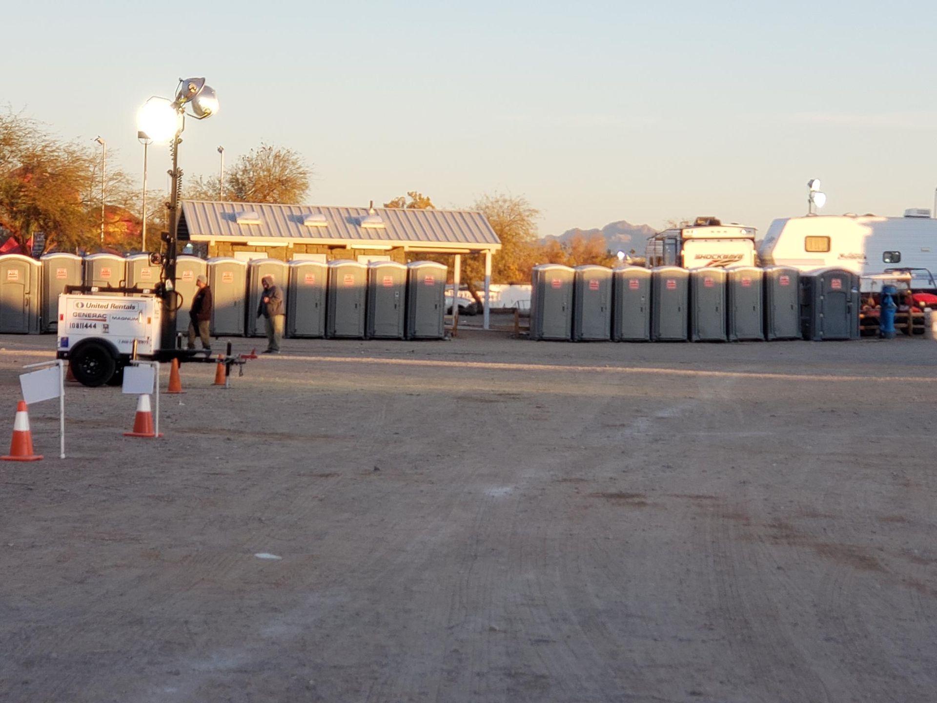 A row of portable toilets are lined up in a parking lot
