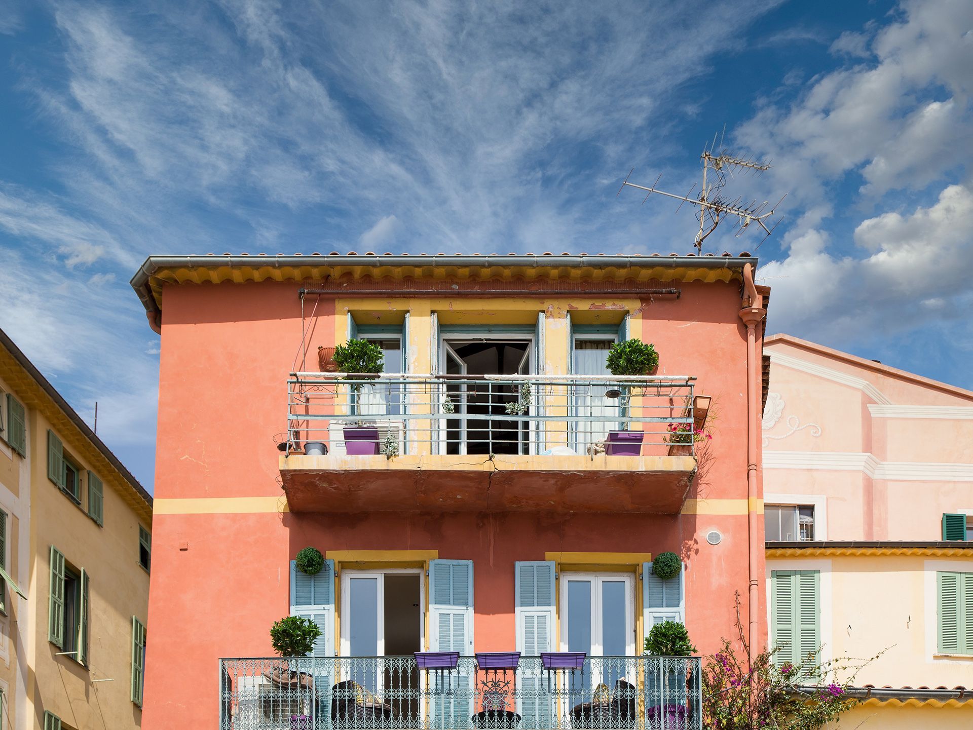 a pink and yellow building with a balcony