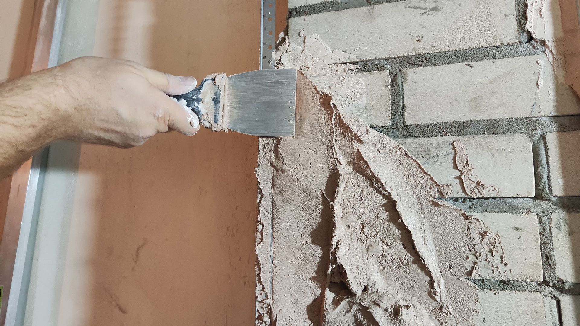 a person is plastering a brick wall with a spatula