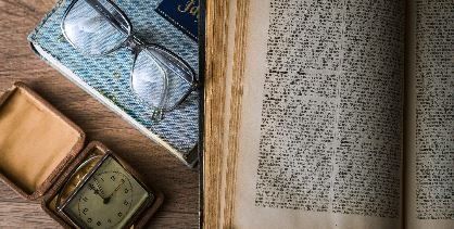 Old book with glasses and clock