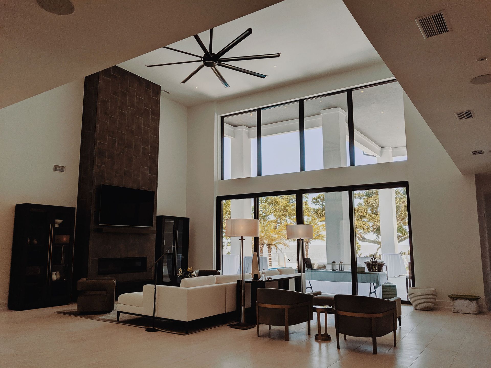 A living room with a lot of windows and a ceiling fan.