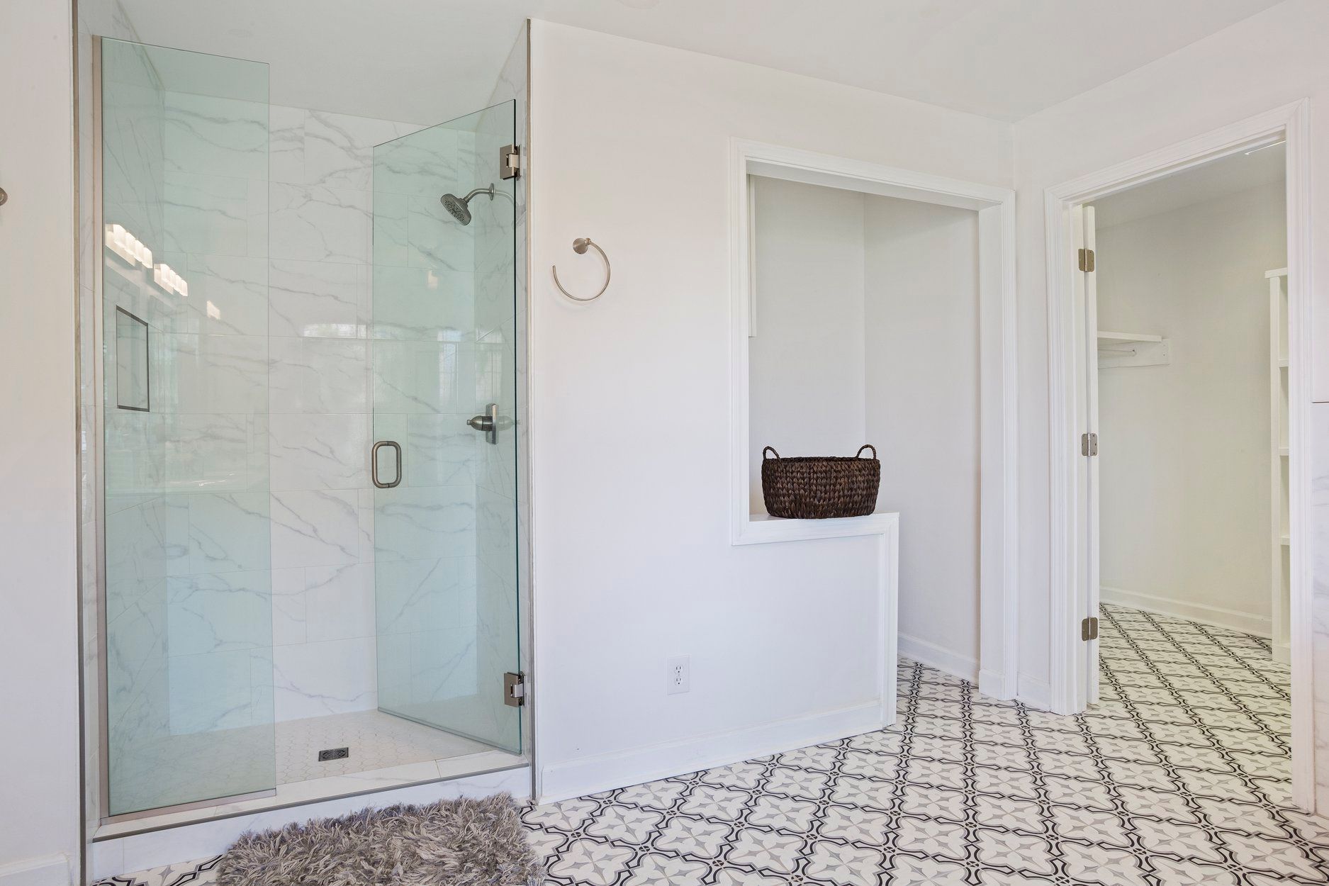 A bathroom with a walk in shower and a black and white tile floor.