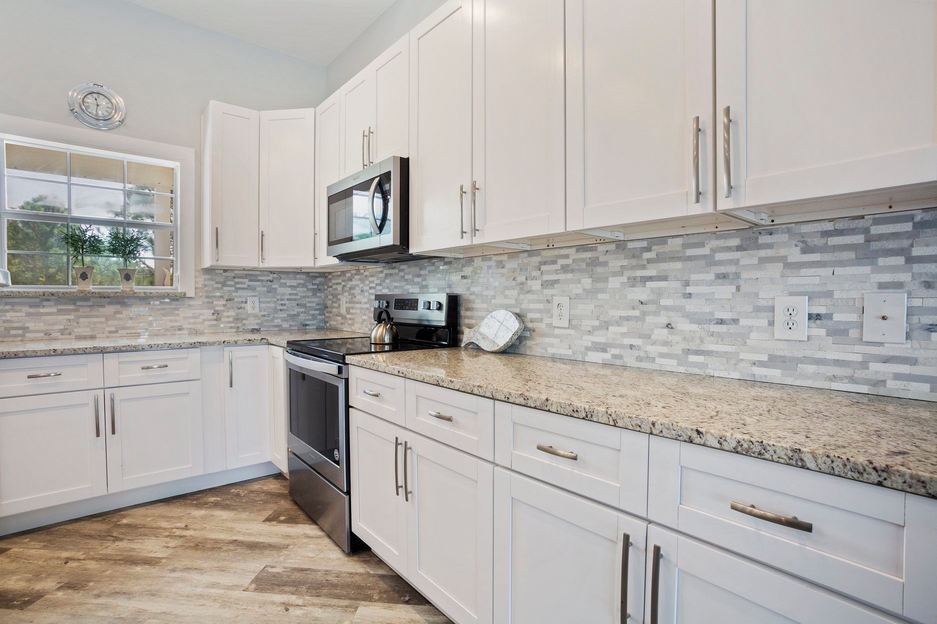 A kitchen with white cabinets , granite counter tops , and stainless steel appliances.