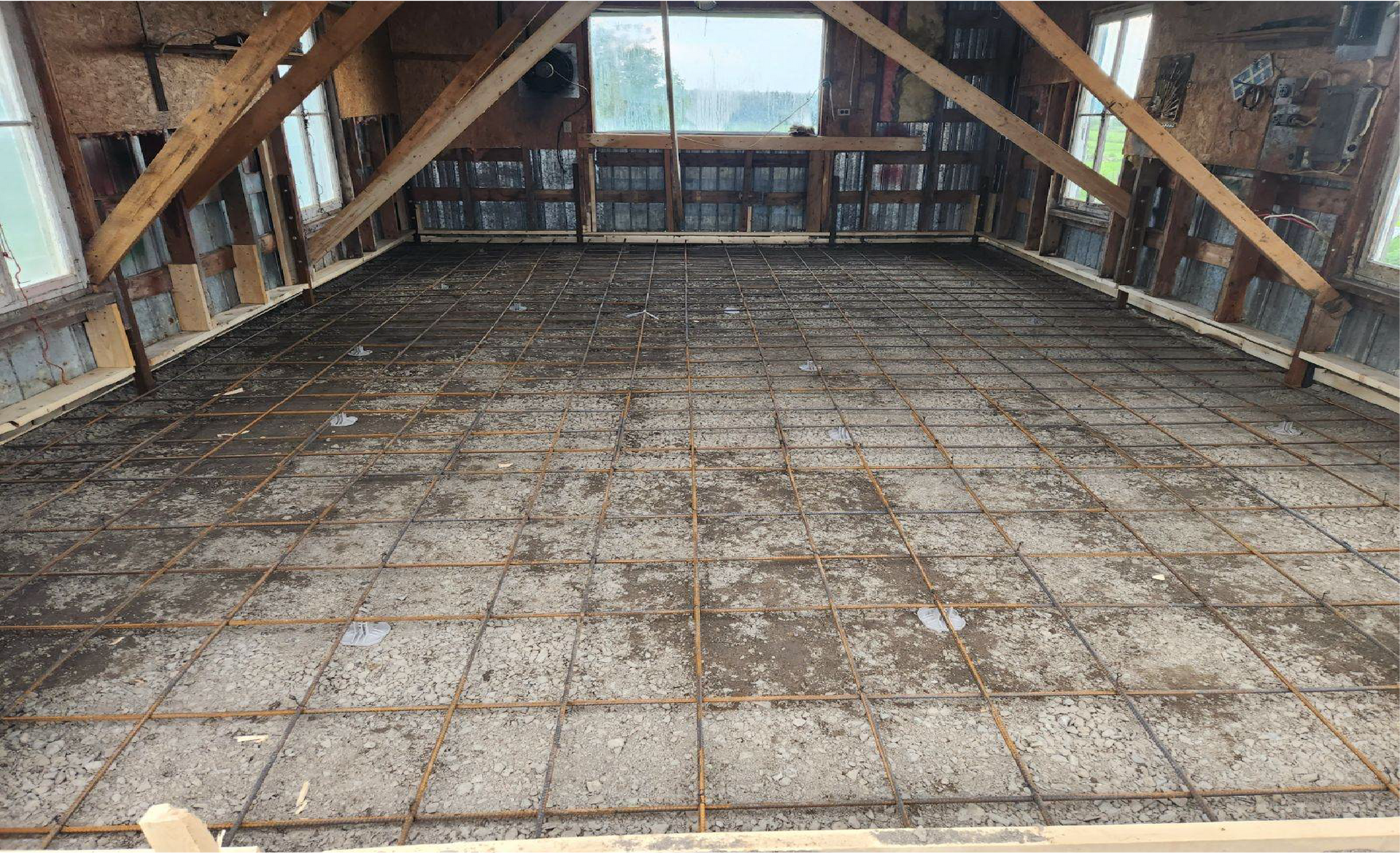 Une grande pièce avec un sol en béton et un toit en bois.