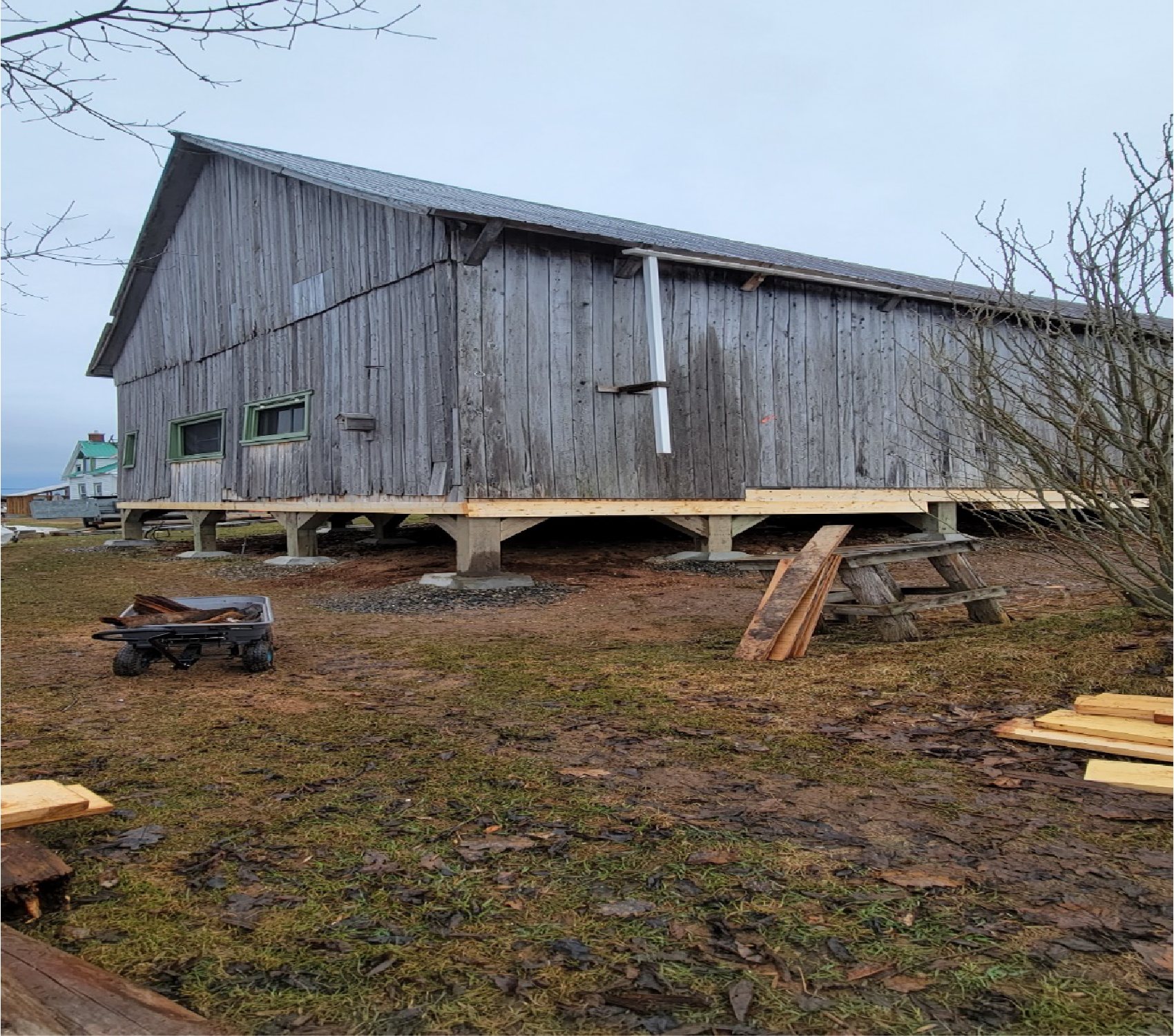 Une grande grange en bois se trouve au milieu d'un champ herbeux.