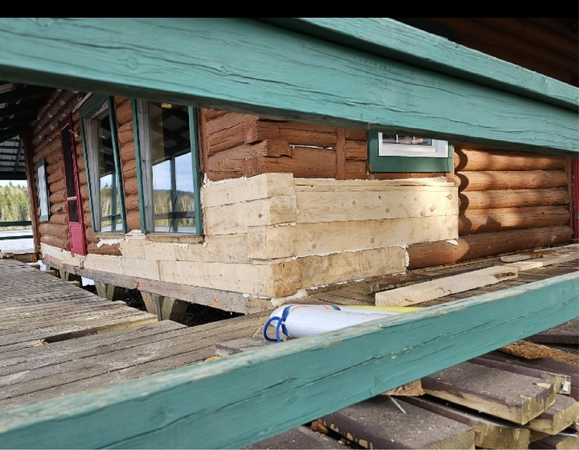 Une cabane en rondins est posée sur une terrasse en bois.