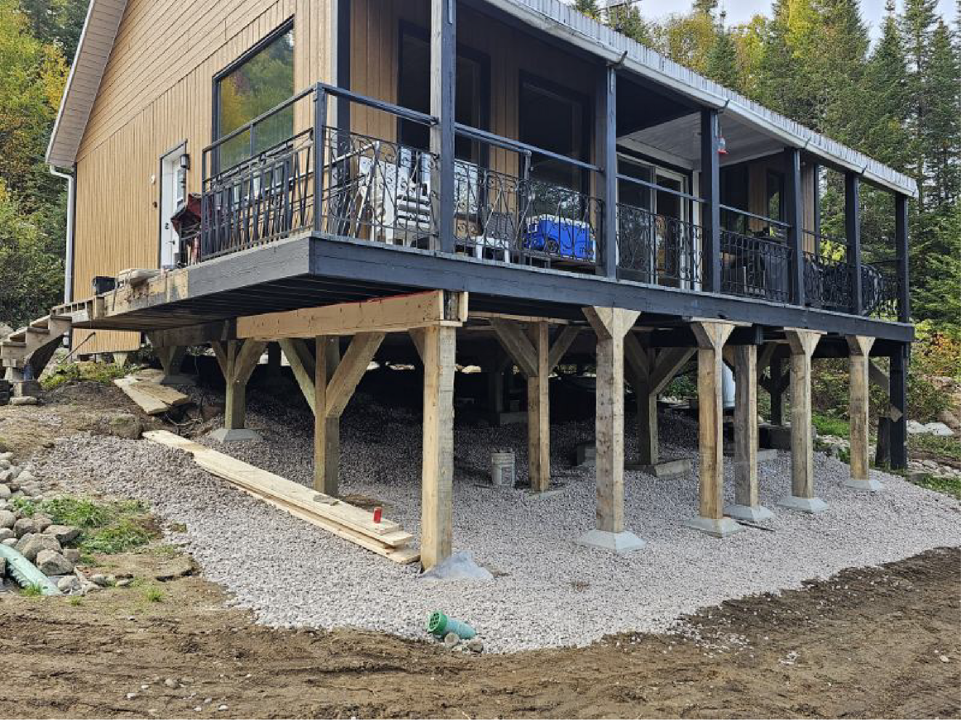 Une maison est en construction sur pilotis avec un grand porche.