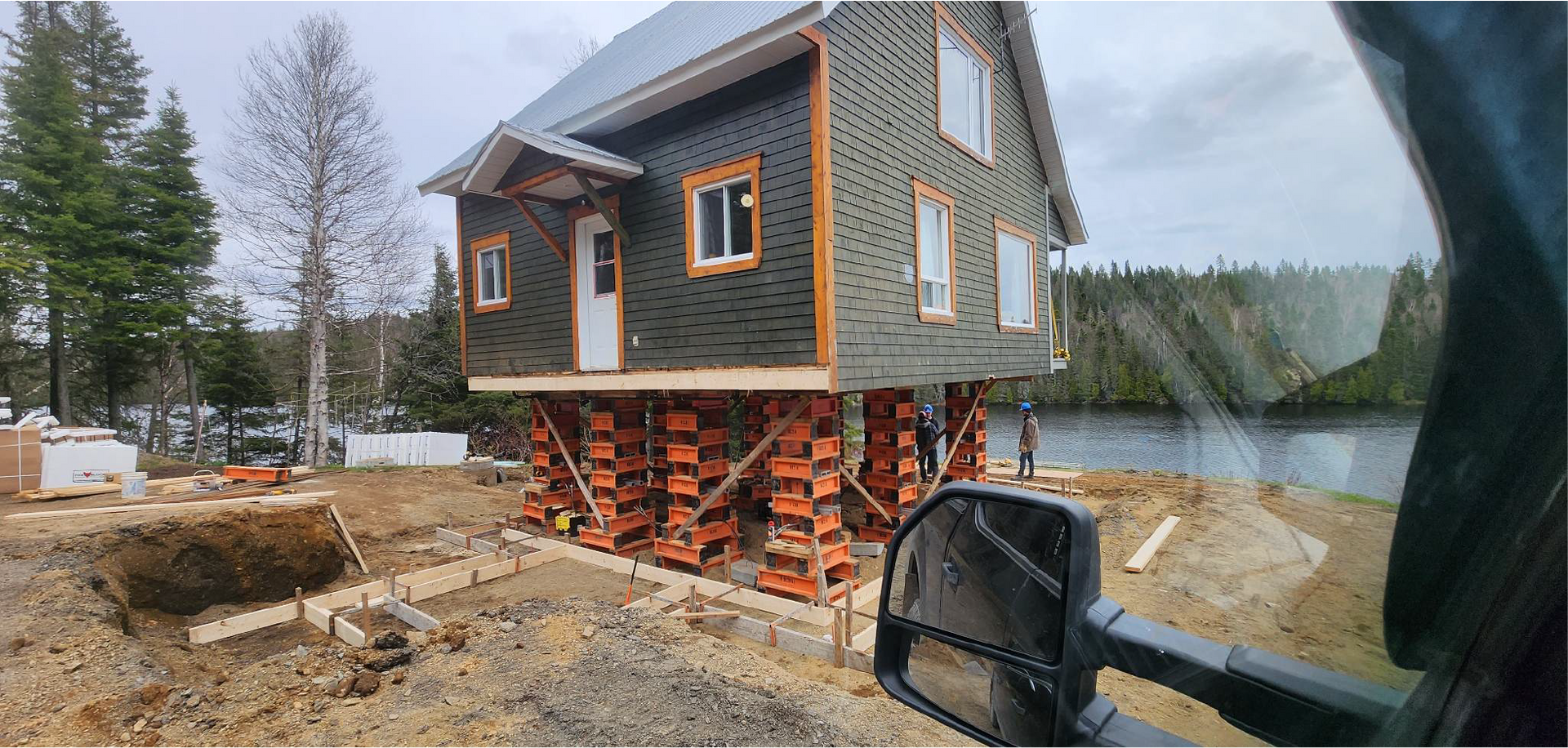Une maison est en construction sur pilotis à côté d'un plan d'eau.