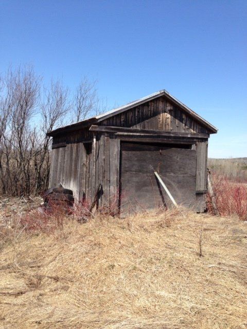 Un vieux hangar en bois se trouve au milieu d'un champ.