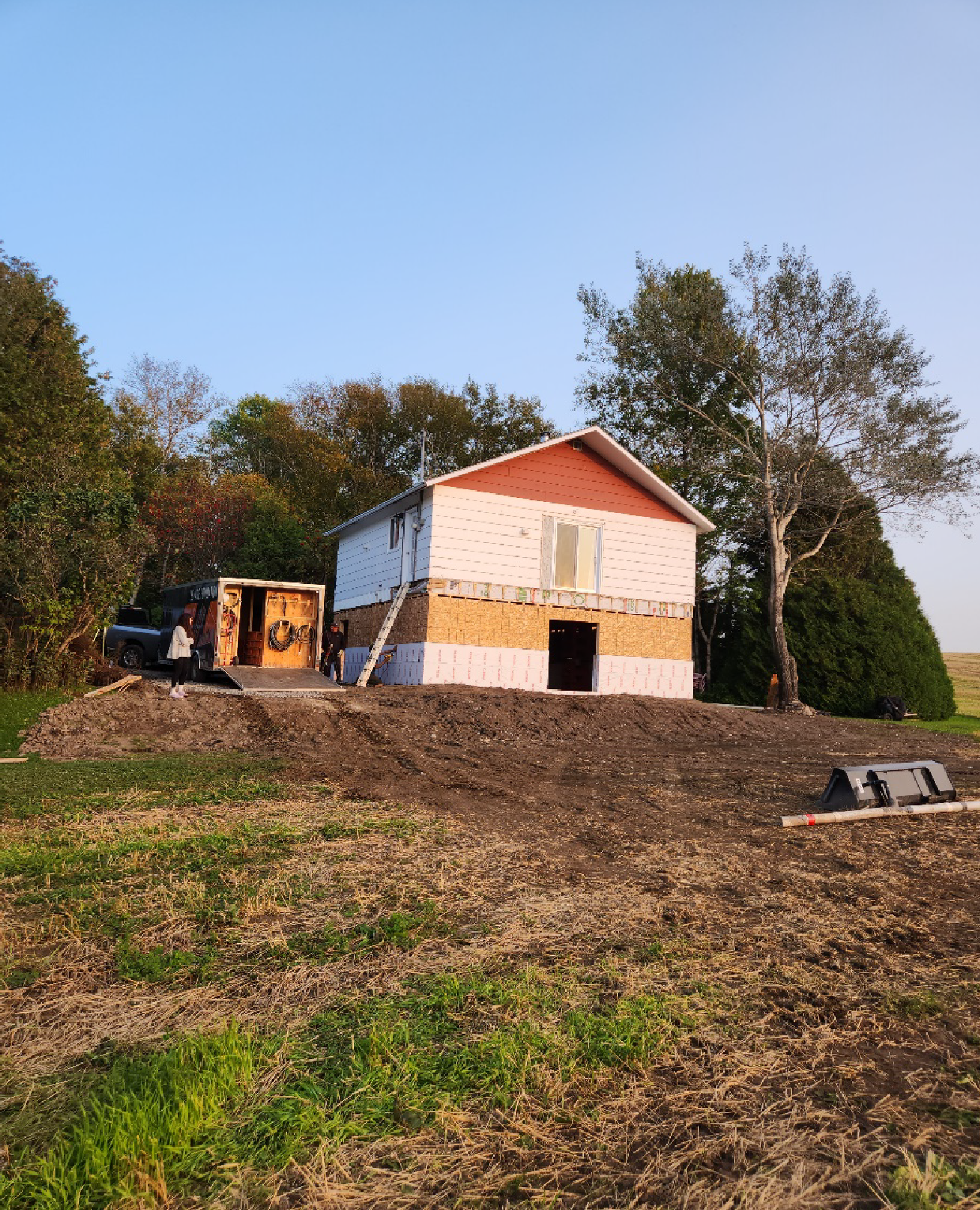 Une petite maison est en construction au milieu d'un champ.