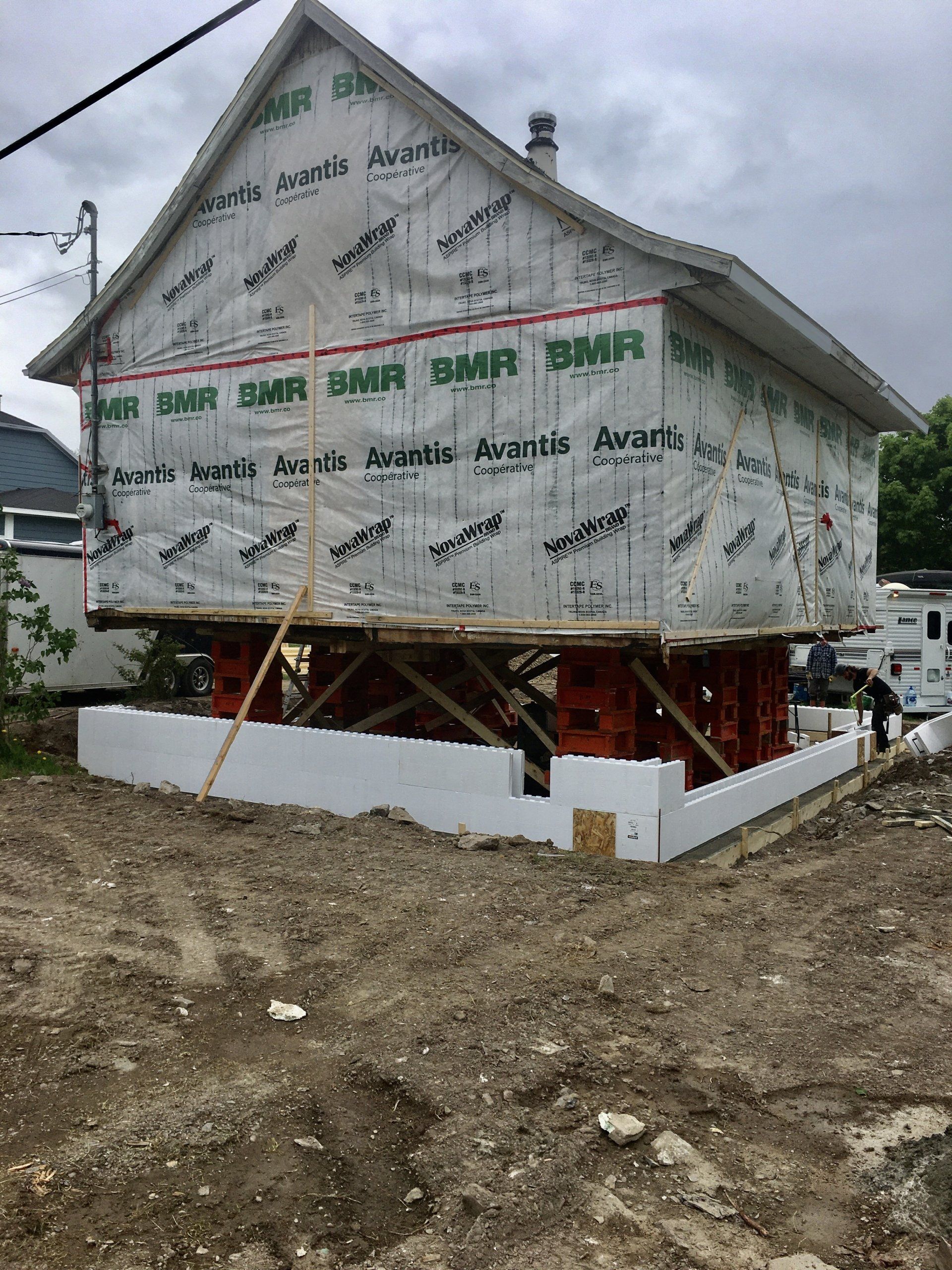 Une maison est en train d'être construite sur pilotis dans un champ de terre.