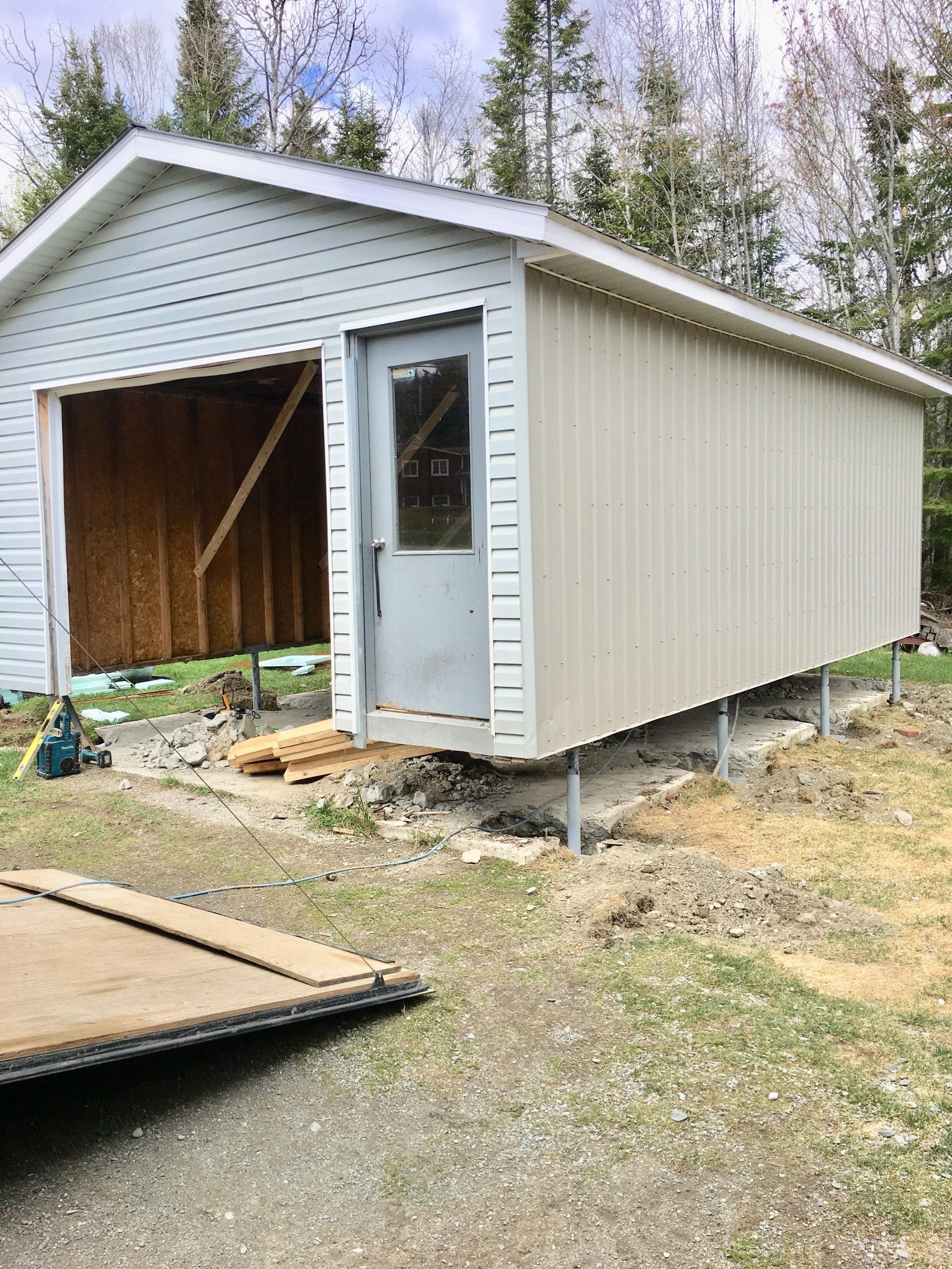 Un garage blanc est en cours de construction dans une cour à côté d'une remorque.